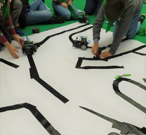 Niños preparando una pista para que circulen coches autónomos de robótica